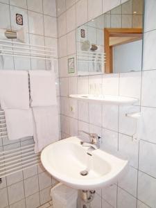 a white bathroom with a sink and a mirror at Gasthaus & Hotel Zur Linde in Friedrichroda