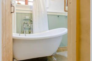 a white bath tub in a bathroom with a shower at The Cow House - In the heart of Whitby in Whitby