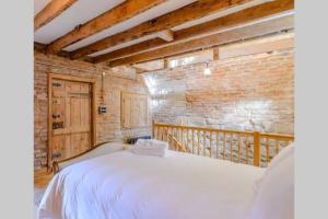 a bedroom with a white bed and a brick wall at The Cow House - In the heart of Whitby in Whitby