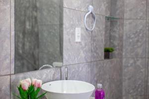 a bathroom with a sink and a mirror and pink flowers at Luxury Flats Ambiente Cristão in Fortaleza