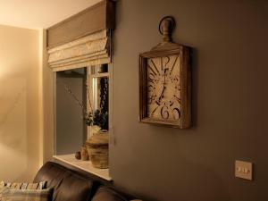 a clock hanging on a wall next to a window at Plum Tree Cottage in Witton le Wear