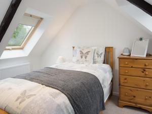 a bedroom with a bed and a dresser and a window at Chatton Cottage in Chatton