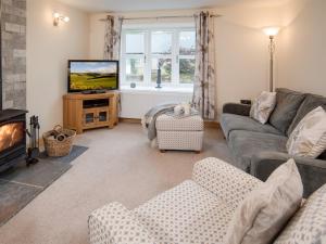 un soggiorno con divano e TV di Chatton Cottage a Chatton
