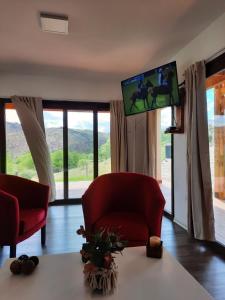 a living room with a red chair and a flat screen tv at La Encantada in Potrero de los Funes