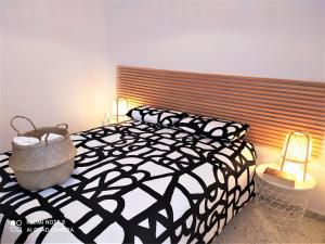 Un dormitorio con una cama y lámparas en blanco y negro. en Ático Galileo, en La Línea de la Concepción