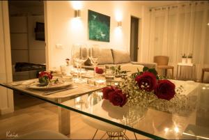 a living room with a glass table with roses and wine glasses at Piso Paseo Marítimo in Benalmádena