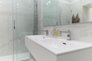 a white bathroom with a sink and a shower at Suite Rodinò 24 in Naples