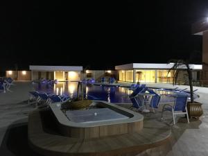 a swimming pool at night with chairs and a table at Golden Lake Apart-Hotel in Arraial do Cabo