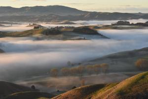 a foggy valley in the hills with trees and mountains at Paratu Farm Cottage in a quiet rural setting. in  Waipukurau