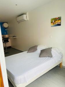 a white bed with two pillows in a room at Résidence VWAL O VAN 2, studio plage à proximité in Sainte-Anne