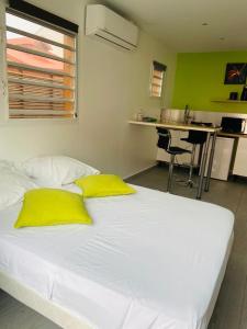 a white bed with yellow pillows in a room at Résidence VWAL O VAN 1, studio plage à proximité in Sainte-Anne