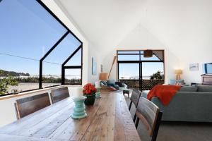 a living room with a wooden table and some windows at Seascapes in Punakaiki