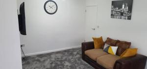 a living room with a couch and a clock on the wall at Exquisite and Modern 2 bed Maisonette in Harmondsworth