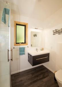 uma casa de banho branca com um lavatório e um espelho em Treescapes em Punakaiki