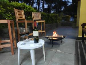 uma garrafa de vinho sentada numa mesa ao lado de uma fogueira em Casa de Campo Lazer Completo Paraíso de Reservas Naturais em Sp em Ibiúna