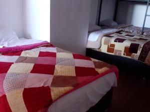 two beds in a room with a colorful quilt at Marvelous Hostel Cusco in Cusco