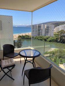 a table and chairs on a balcony with a view of the ocean at Departamento Papudo Laguna Vista al Mar y Laguna in Papudo