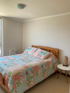 1 dormitorio con 1 cama con un edredón colorido en Departamento Papudo Laguna Vista al Mar y Laguna en Papudo