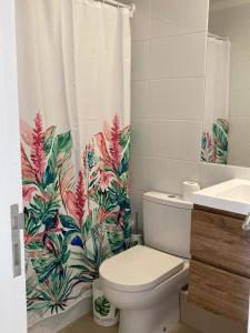 a bathroom with a toilet and a tropical shower curtain at Departamento Papudo Laguna Vista al Mar y Laguna in Papudo