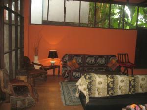 a living room with orange walls and a couch and chairs at Teak house Chiang Mai in Chiang Mai