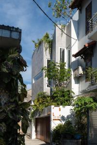 a tall white building with plants on the side of it at LIMDIM HERE in Hue