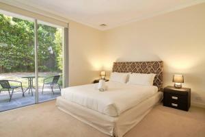 sypialnia z dużym łóżkiem i patio w obiekcie Premium 2 Bedroom Garden Apartment w mieście Warrawee