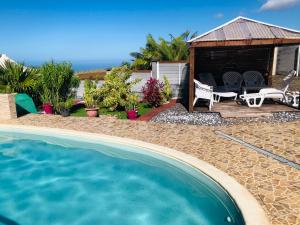 a house with a swimming pool and a gazebo at Au Champ de Cannes in Petite Île