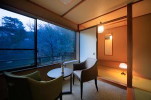 a room with a table and chairs and a window at Naruko Fuga in Osaki