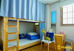 a bedroom with two bunk beds with a desk and a desk at Ganderak Guesthouse in Jeju