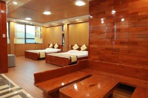 a room with two beds and a wooden wall at Gold Hotel in Cao Bằng