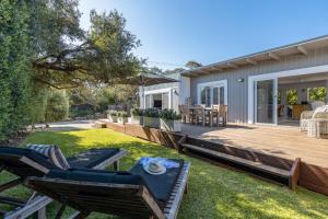 a backyard with a wooden deck and chairs at Grand Capella Villa 1 in Blairgowrie