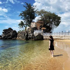 a woman walking in the water on the beach at Nipola Hotel - Chợ Đêm Dương Đông Phú Quốc in Phú Quốc