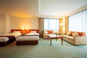 a hotel room with two beds and a couch at Hotel Io Alpheratz in Kasama +30 photos