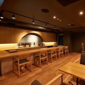 鎌倉市にあるKAMAKURA Hotelの木製のテーブルと椅子が備わるレストランのバー