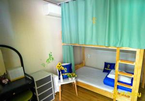 済州市にあるガンデラ ゲストハウスのベッドルーム1室(青いカーテン付きの二段ベッド1組付)
