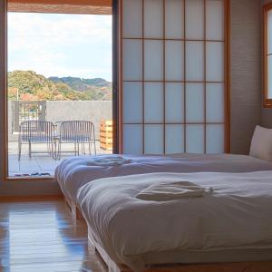 a bedroom with a bed and a balcony with chairs at KAMAKURA Hotel in Kamakura