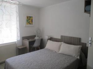a bedroom with a bed and a desk with a chair at Hotel Du Commerce in Pont-Saint-Esprit