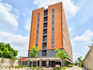 ein hohes rotes Backsteingebäude mit Bäumen davor in der Unterkunft Collection O 92440 Urban Town Apartment Karawang in Telukjambe