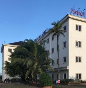a hotel with palm trees in front of it at Hotel Arisu in Serang