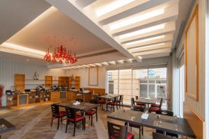 a dining room with tables and chairs and a kitchen at Sama Muscat Hotel in Al Khawḑ