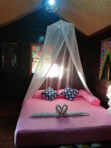 a bedroom with a bed with a mosquito net at Lampang Lanna Home in Lampang