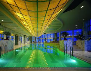 een groot zwembad in een gebouw met blauwe verlichting bij Grand Hyatt Shanghai in Shanghai