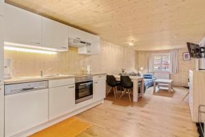 a kitchen with white cabinets and a dining room at Haus Berghof in Schröcken