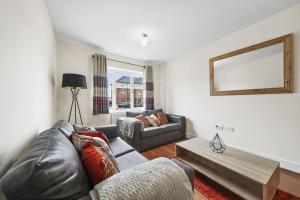 een woonkamer met een leren bank en een tafel bij London Heathrow Living Holywell Serviced Houses - 3 and 4 bedrooms By Ferndale in Stanwell