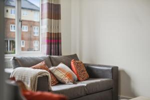 - un canapé avec des oreillers dans le salon dans l'établissement London Heathrow Living Holywell Serviced Houses - 3 and 4 bedrooms By Ferndale, à Stanwell
