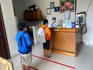 two people wearing face masks standing at a cash register at Suwardika Homestay & Dormitory in Sanur