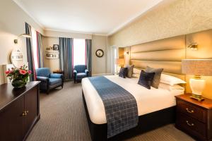 a hotel room with a large bed and a chair at The Bailey's Hotel London Kensington in London