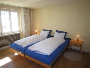 شاليه آييني في جريندلفالد: غرفة نوم بسرير ازرق وملاءات بيضاء ونافذة