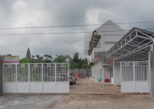 a building with a white gate next to a parking lot at RedDoorz Syariah near Wisata Situ Gunung Sukabumi in Kadudampit