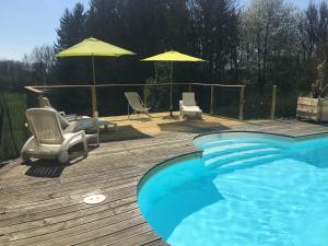 - une piscine avec des chaises et des parasols sur une terrasse en bois dans l'établissement gîtes des planchettes, à Marigny